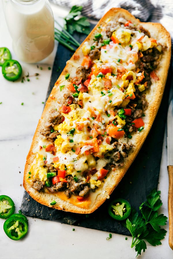 Sausage stuffed French bread bowl on a black cutting board.