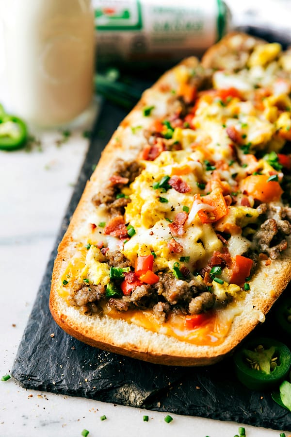 Sausage stuffed French bread bowl on a black cutting board.