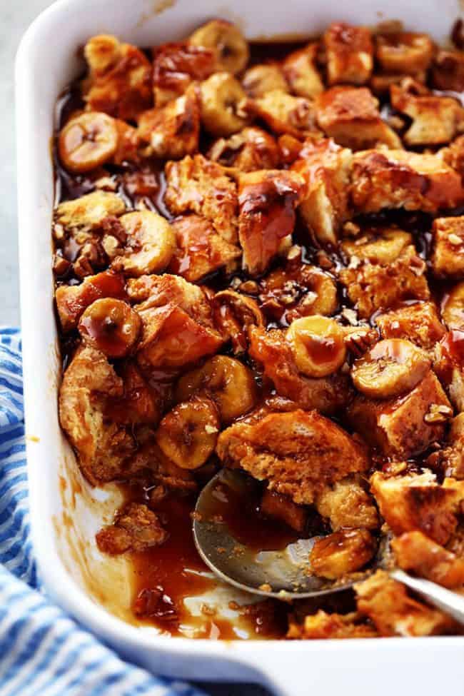 Overnight caramel of banana French toast with caramel syrup and a white casserole dish with a silver spoon.