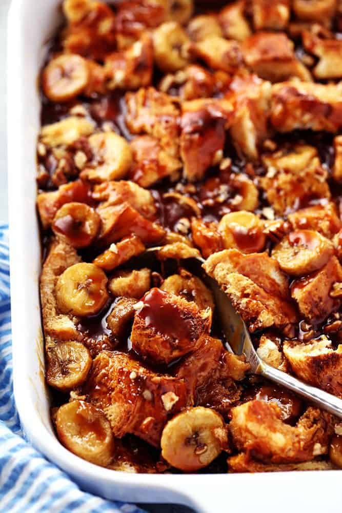 Overnight Caramel banana French toast and a casserole dish with caramel syrup over top with the spoon on the side.