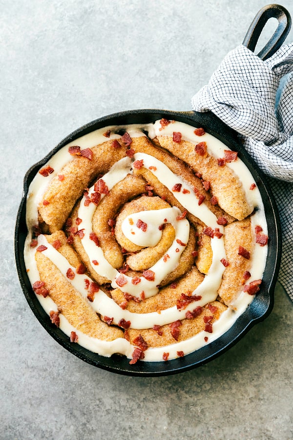 Maple bacon cinnamon roll in a black skillet.