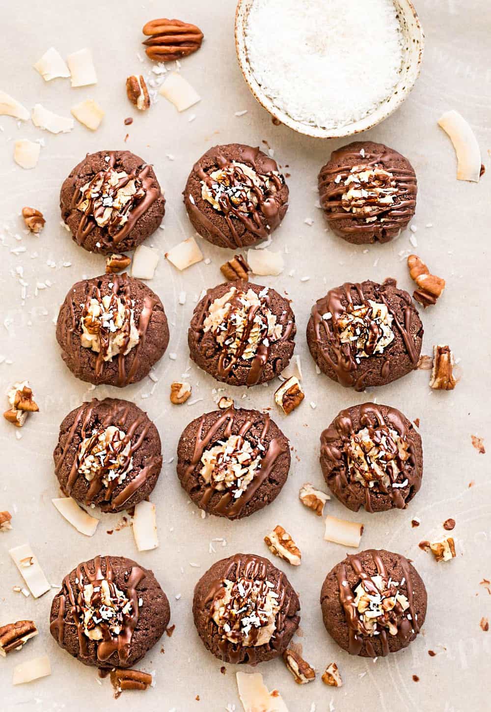 12 German chocolate thumbprint cookies lined up and rolled garnished with walnuts and coconut.