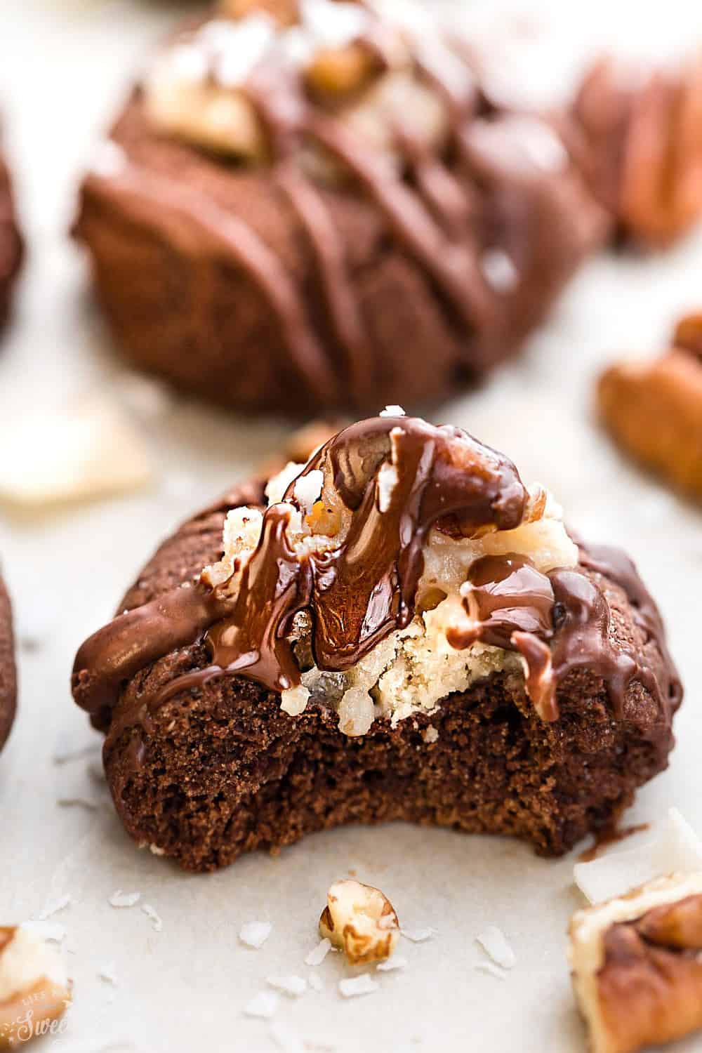 One German chocolate thumbprint cookie with a bite taken out of it.