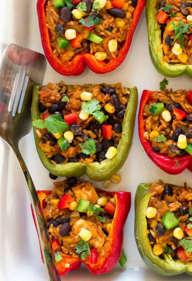 Chicken enchiladas the peppers lined up with a spatula on the left-hand side in a white dish.