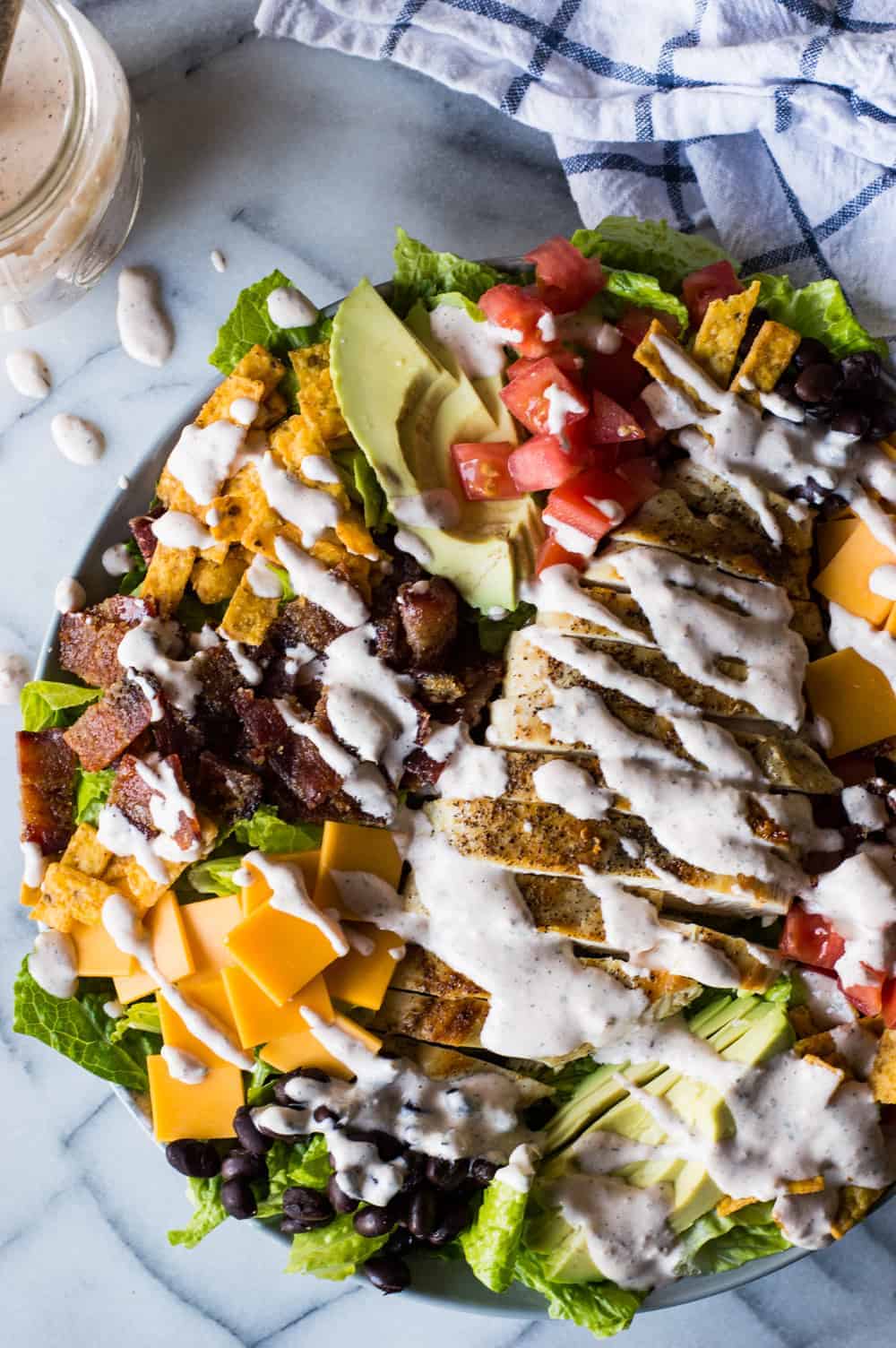 Southwest Grilled Chicken Salad with Candied Bacon. This salad is loaded with grilled chicken, fresh juicy tomato, creamy avocado, crunchy tortilla strips, black beans, cheddar cheese, and sweet and salty candied bacon. All drizzled with a homemade salsa ranch that is truly addicting!