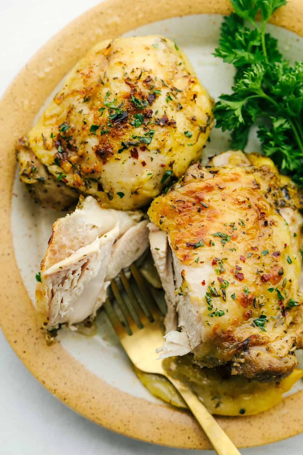 Greek Lemon chicken on a plate, and cut by a fork.