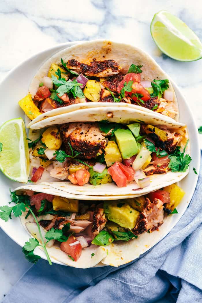 Grilled Spicy Blackened Salmon Tacos with Pineapple Avocado Salsa on a white plate.