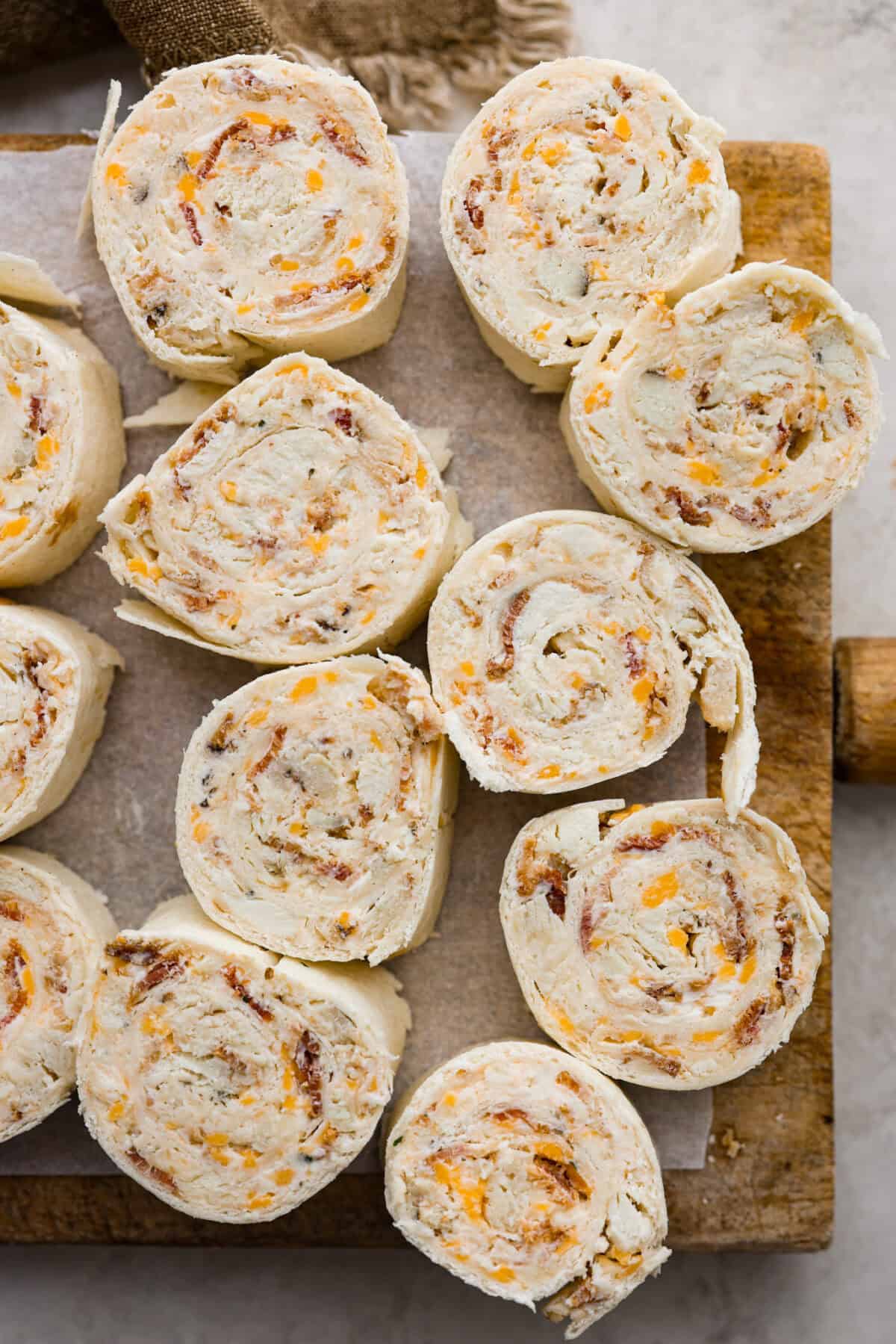 Overhead shot of chicken bacon ranch pinwheels on a wooden cutting board. 