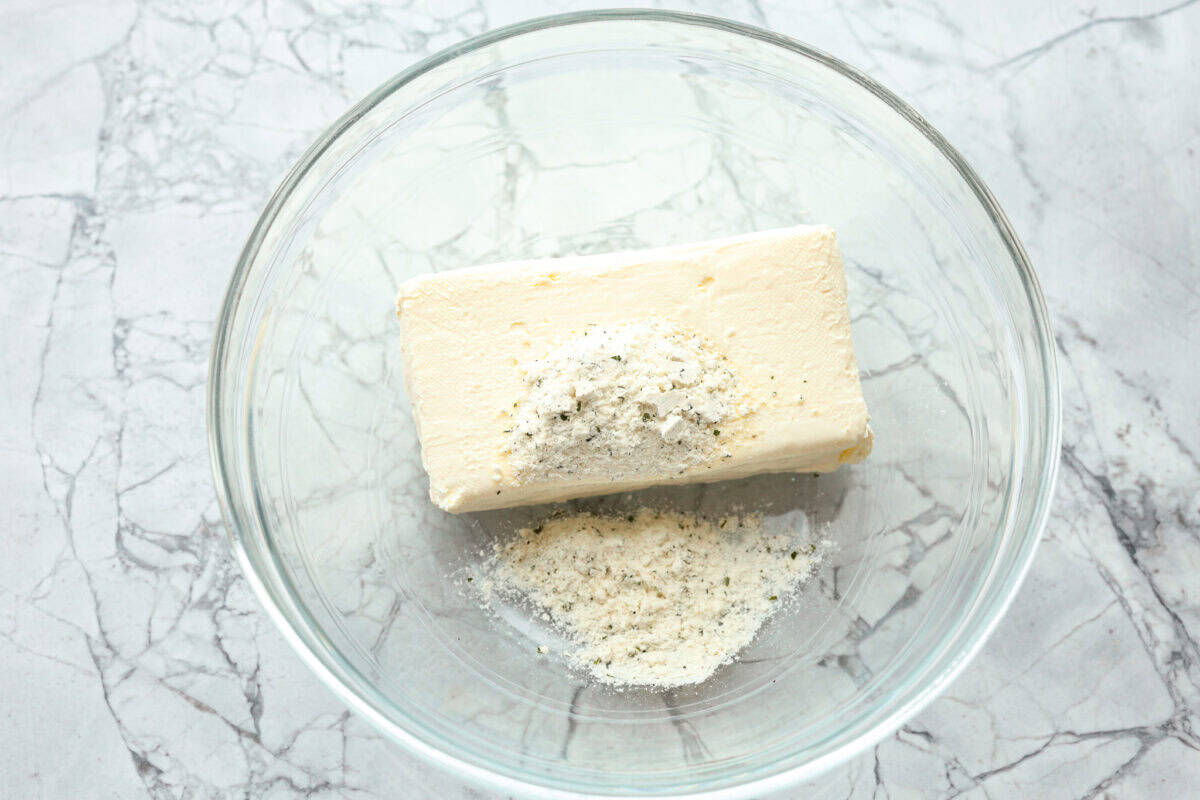 Overhead shot of cream cheese and ranch seasoning in a glass bowl. 