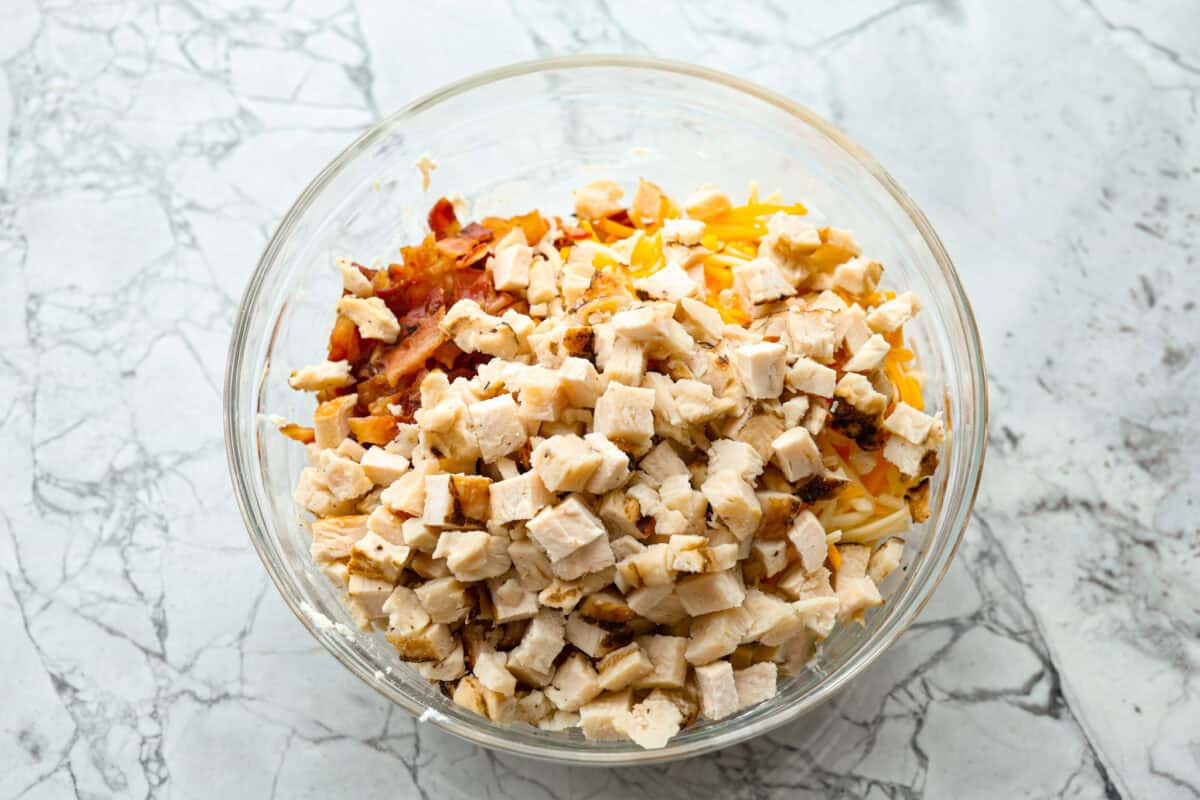 Overhead shot of chicken, bacon and cheese over the cream cheese mixture in a bowl. 