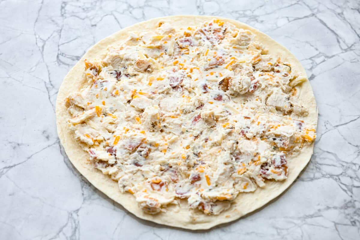 Overhead shot of tortilla with filling mixture spread over the top. 