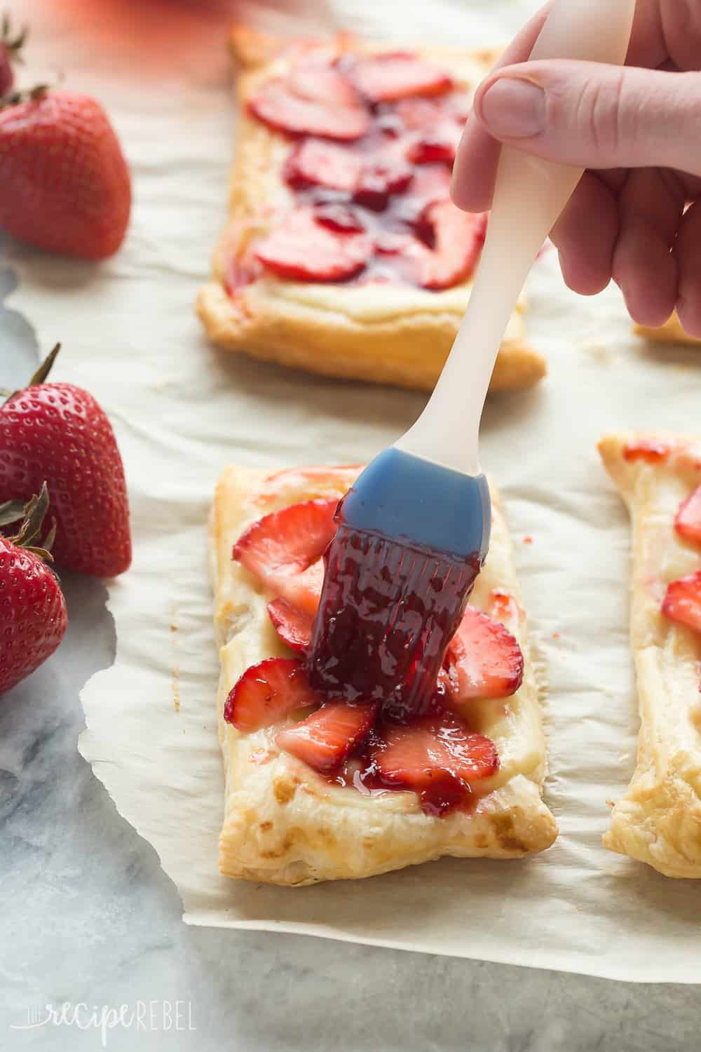 Brushing glaze on Strawberry Cream Cheese Danishes. 