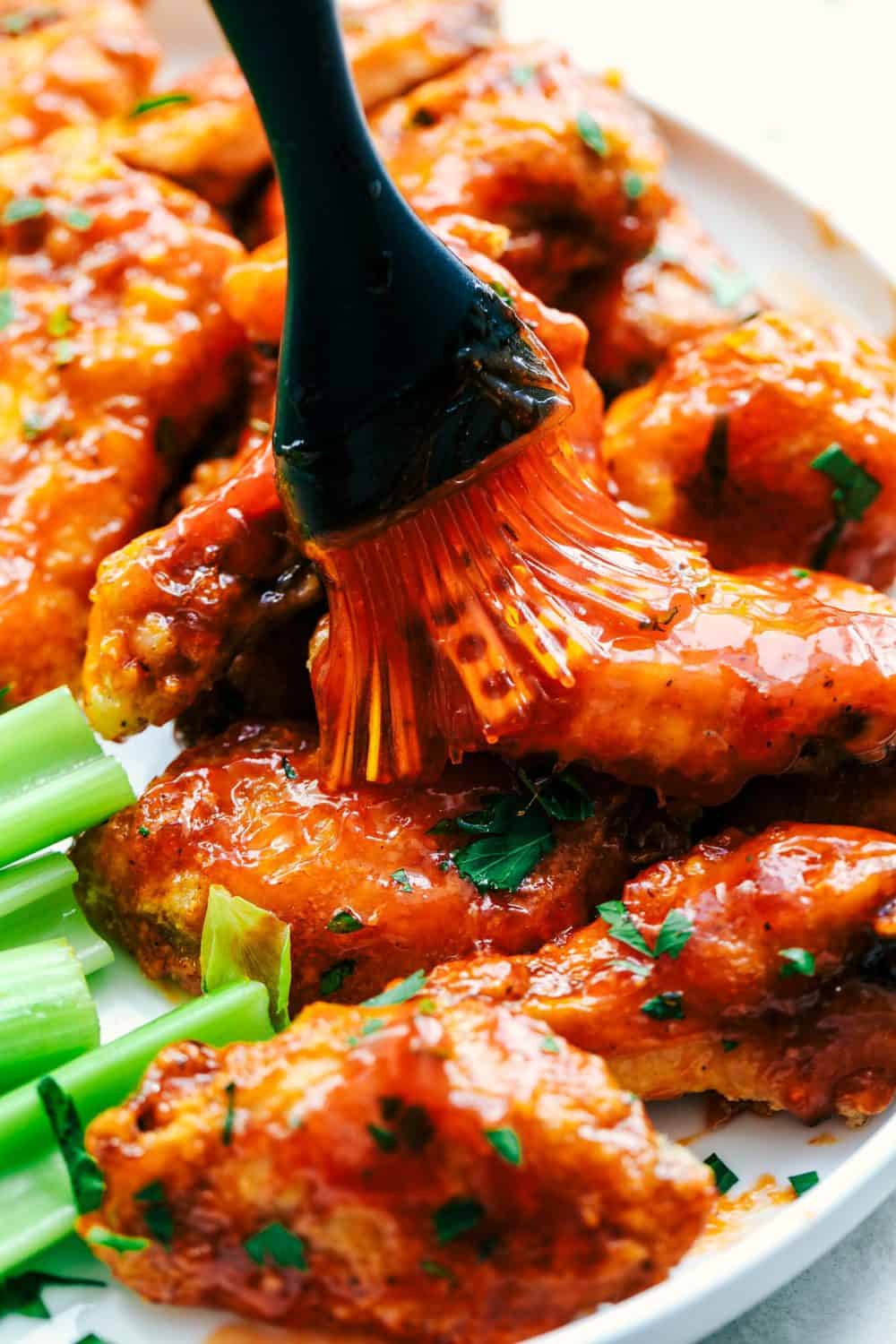 Baked Sticky Honey Garlic Buffalo Wings being brushed with sauce.