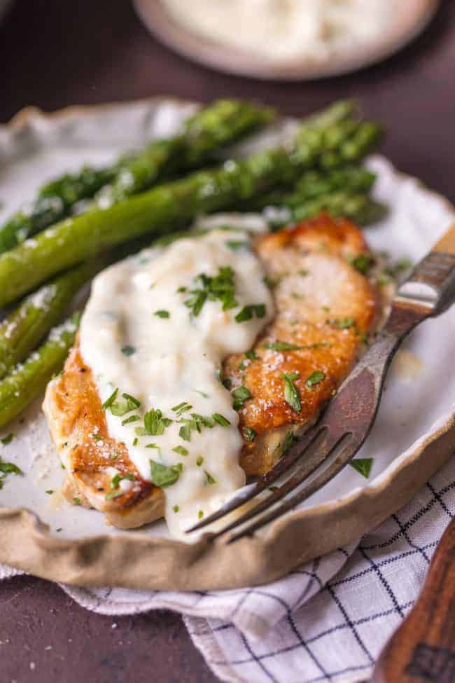 A plate of Creamy Parmesan Pork Chops with asparagus.