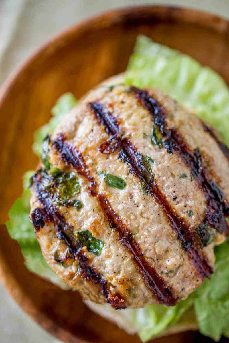 Crazy flavorful, moist and tender Spinach Feta Turkey Burger with lettuce on a wooden plate..