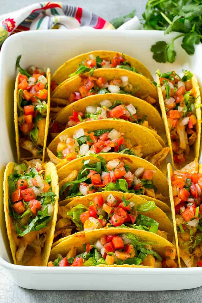 Baked Chicken Tacos stcked in rows in a baking dish.