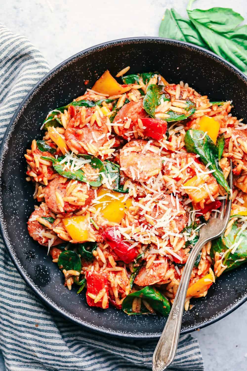 Italian Sausage and Vegetable Orzo Skillet on a black plate.