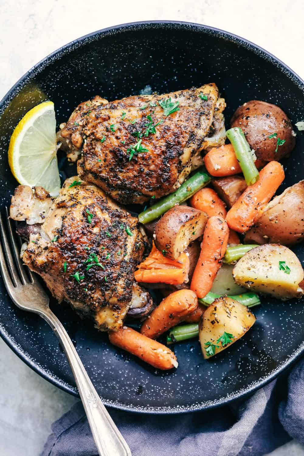 Slow Cooker Lemon Garlic Chicken Thighs and Veggies on a black plate.