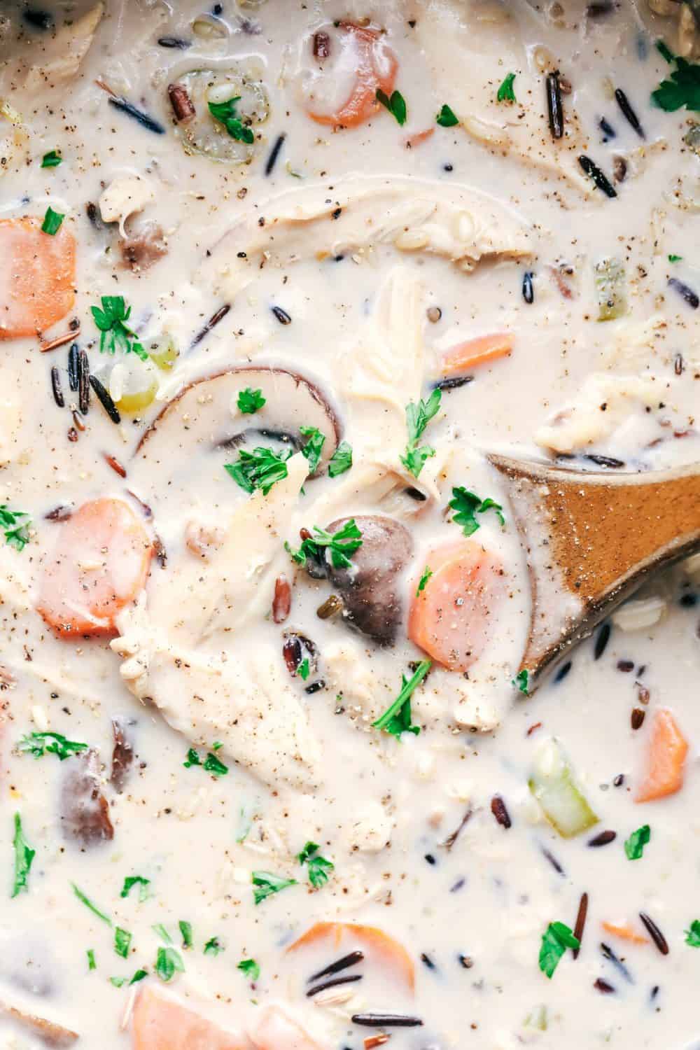 Creamy Turkey Wild Rice Soup being stirred by a wooden spoon.