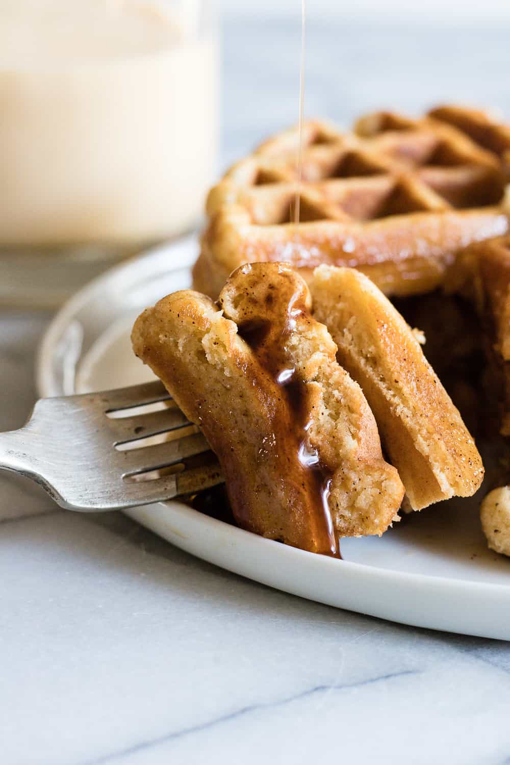 A bite on a fork of light and fluffy waffles. 