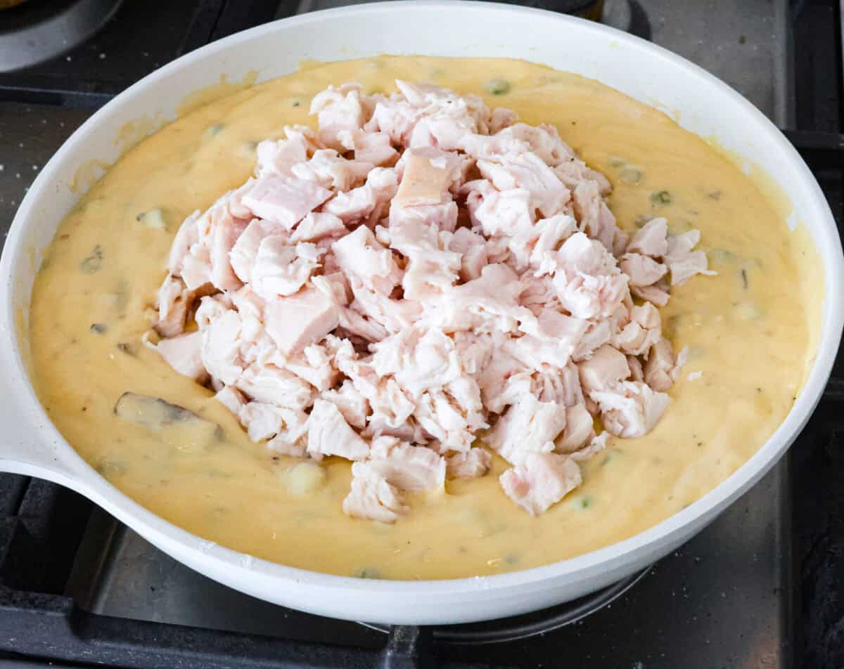 Overhead shot of veggies with soup mixture and chicken on top. 