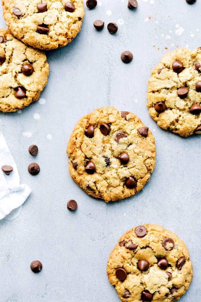 Chewy oatmeal cookies with chocolate chips on top and chocolate chips next to the cookies. 