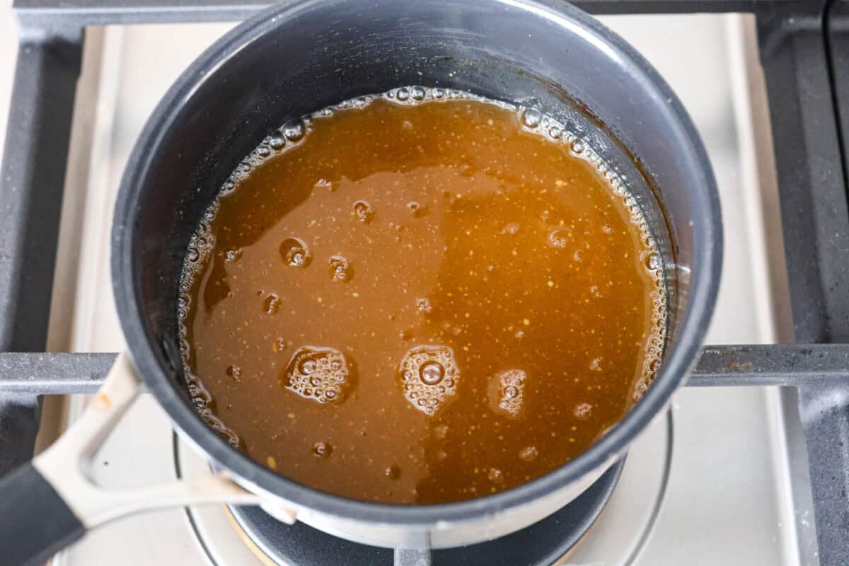 Overhead shot of pineapple glaze ingredients in a saucepan on the stove top. 