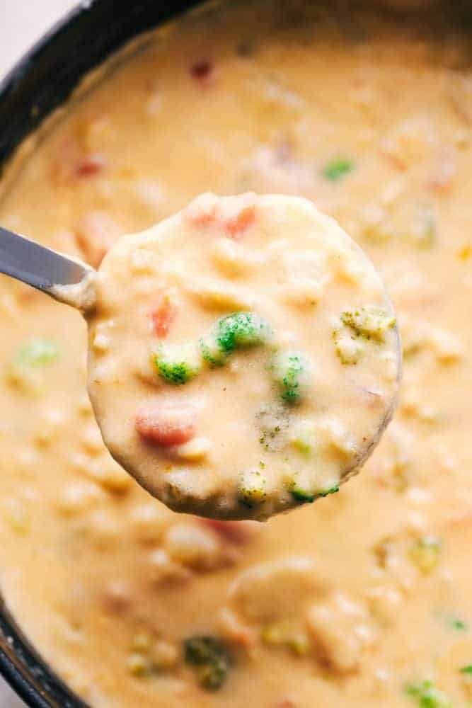 Cheesy Vegetable Soup being spooned out of a bowl.