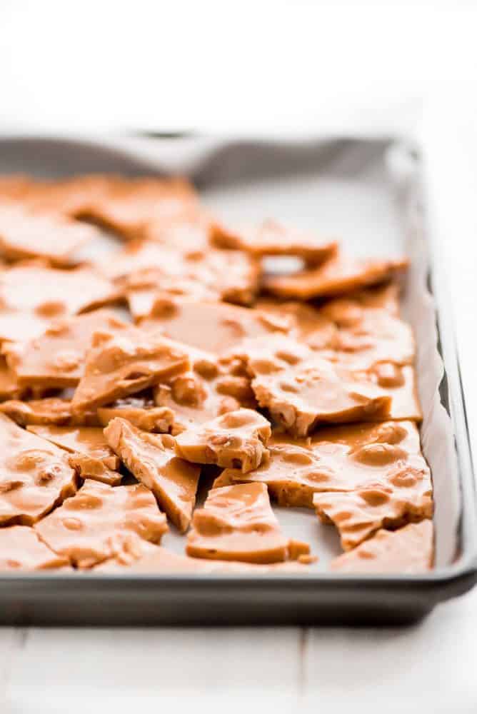 peanut brittle in a sheet pan laying on top of parchment paper. 