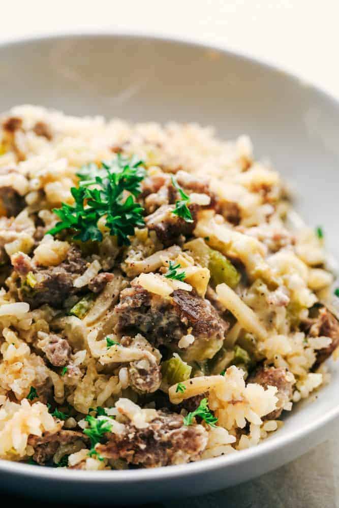 Easy Sausage and Rice Casserole in a white bowl with garnish on top. 