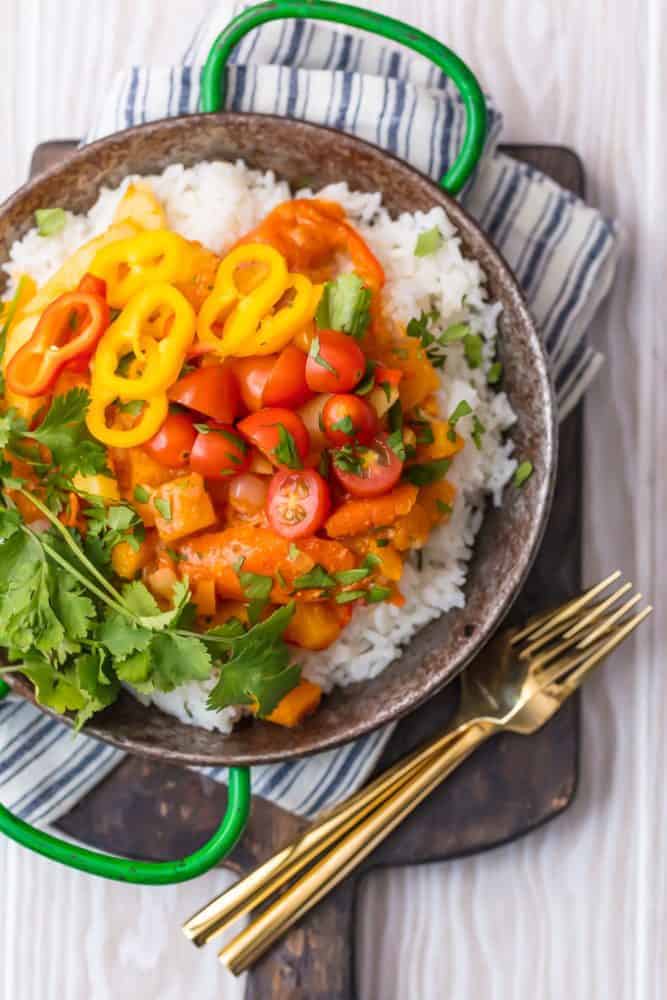 Vegetable Curry over white rice in bowl with forks on a cutting board. 