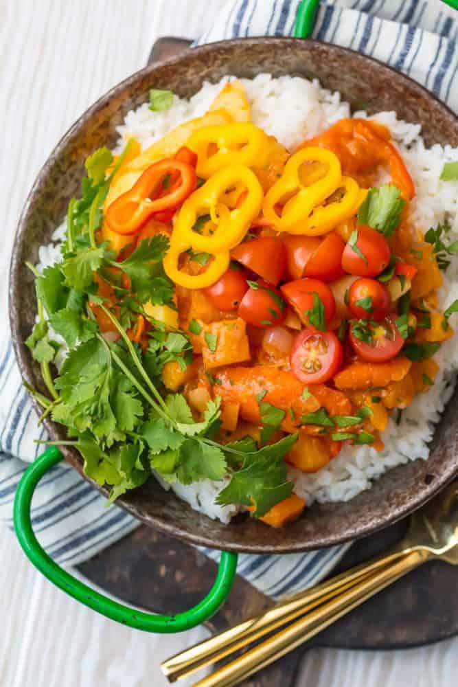 Vegetable Curry over white rice in a bowl with forks on a cutting board. 