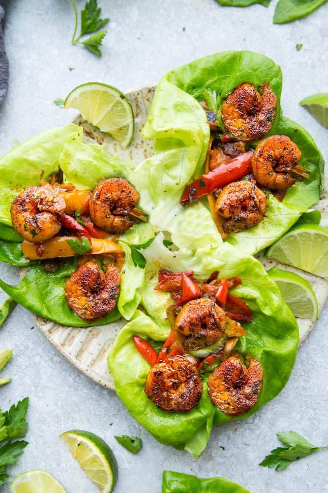 Cilantro Lime Shrimp Lettuce Wraps on a tan plate with sliced lime on the side. 