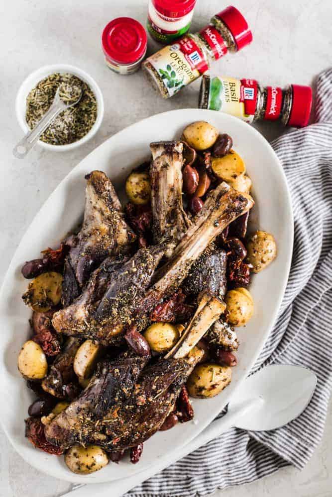 Slow Cooker Greek Lamb Shanks on a white platter with McCormick seasonings. 