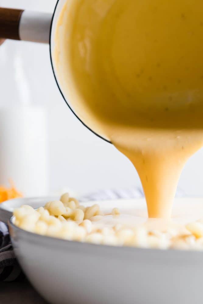 Cheese being poured over macaroni. 