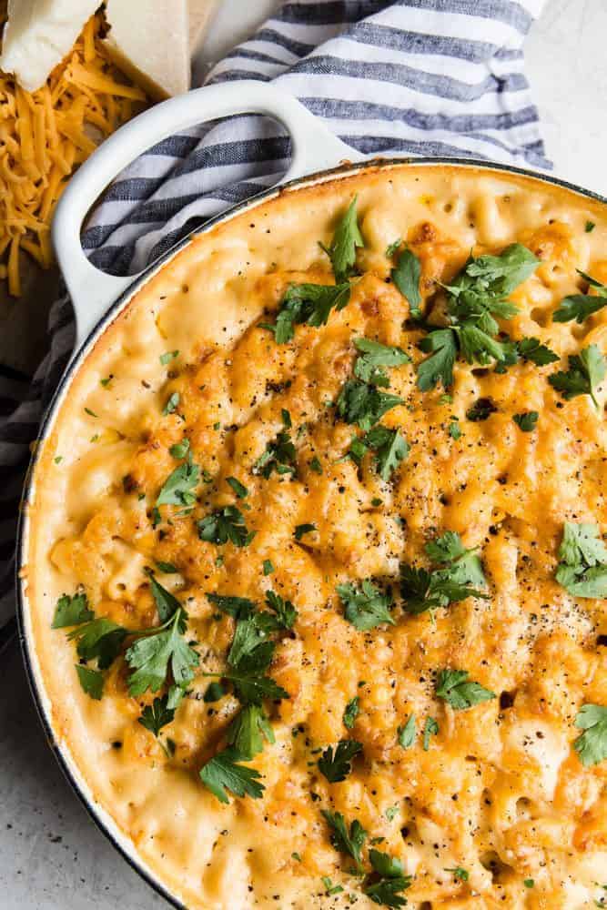 Baked Macaroni and Cheese in a white pot with a grey and white cloth. 