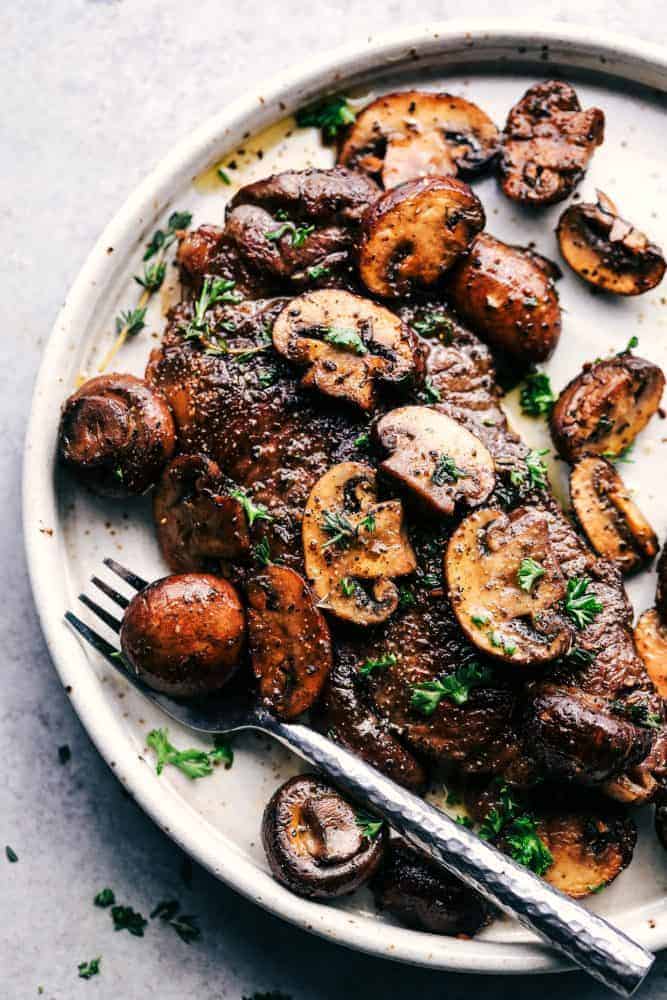 Garlic Butter Herb Steak and Mushroom on a white plate with a metal fork. 