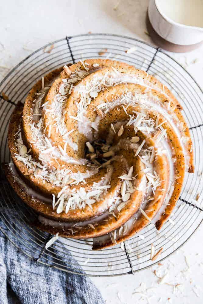 Bundt cake on a cooling rack with almond slices on top. 