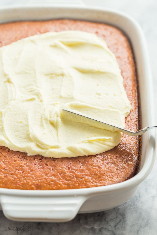 Lemon frosting on strawberry cake in a white pan. 