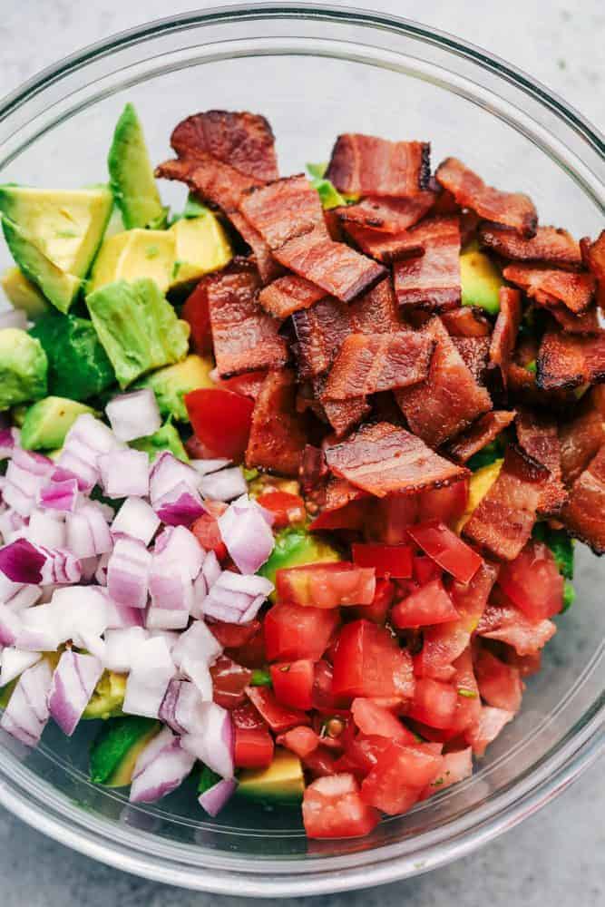 Ingredients for Bacon Guacamole in a clear bowl. 