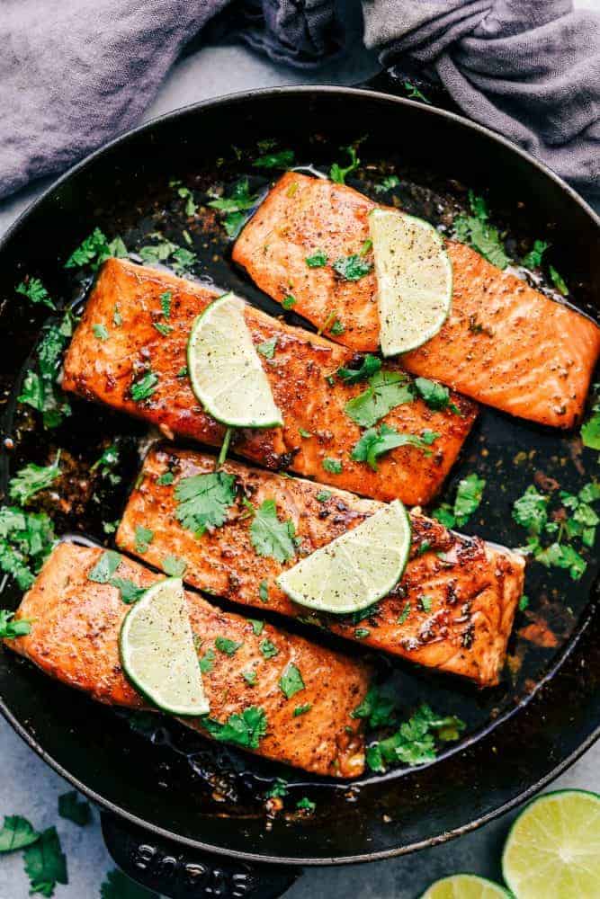 Cilantro Lime Butter Salmon in a skillet with sliced lime on top of the salmon. 