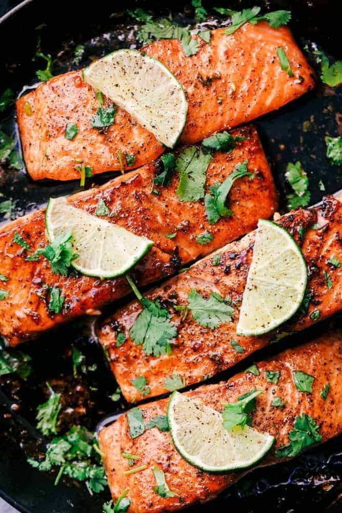 Cilantro Lime Butter Salmon in a skillet with sliced lime on top. 