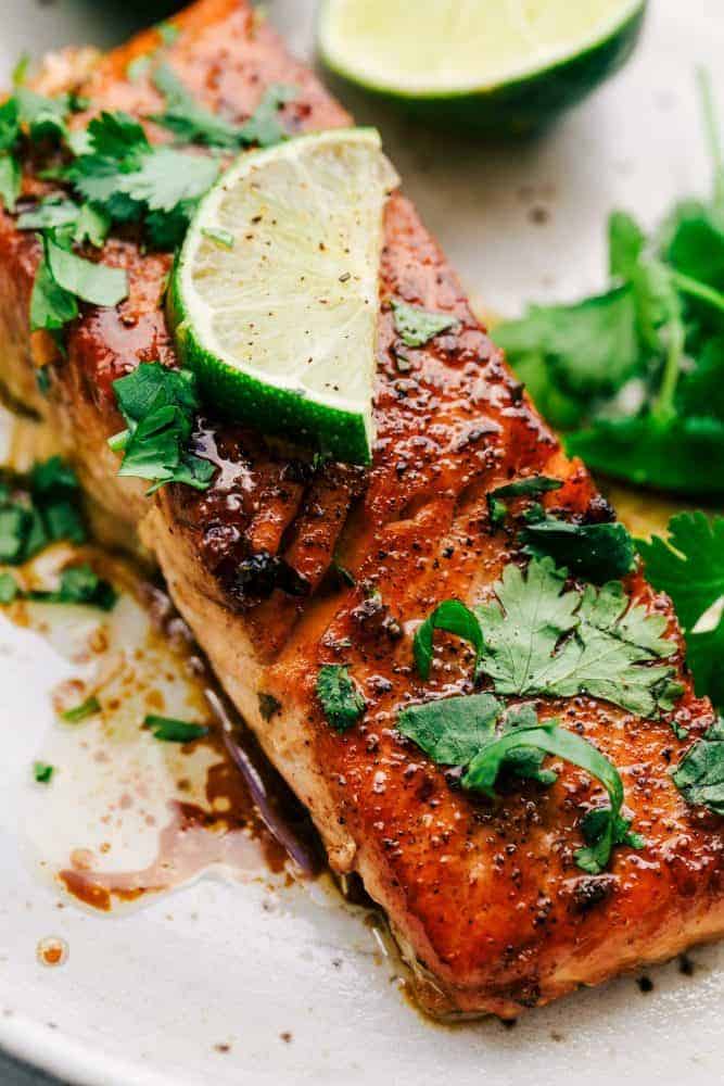 Cilantro Lime Butter Salmon on a white plate with sliced lime on top. 