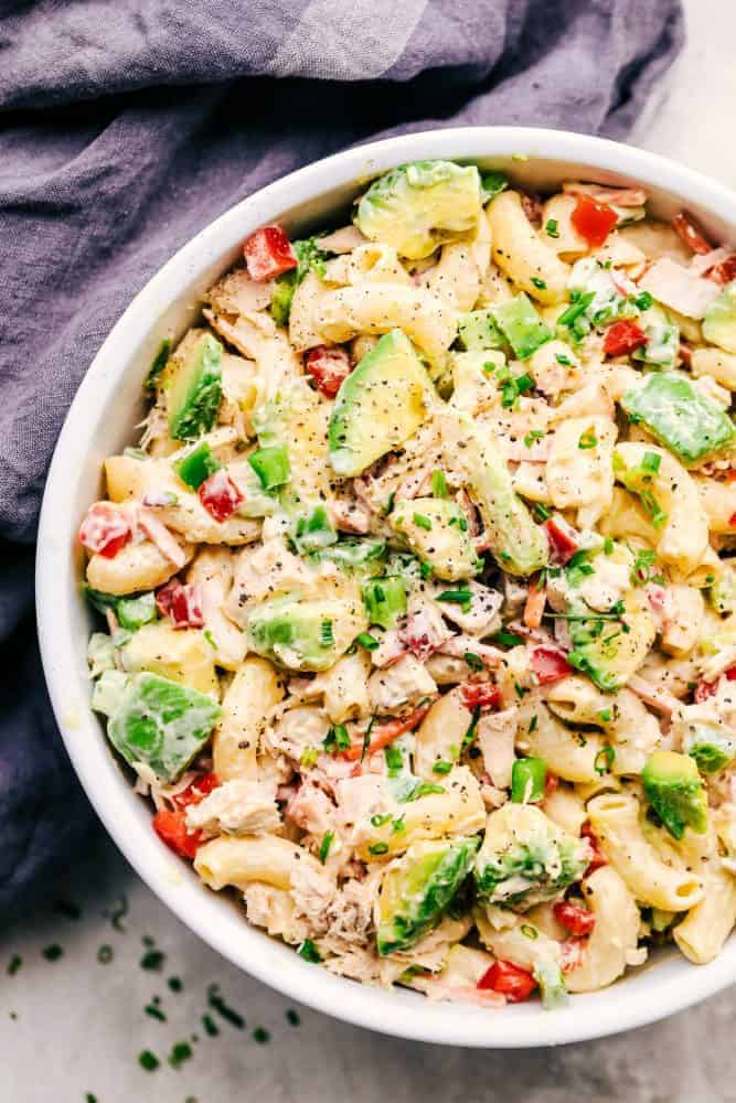 Tuna Avocado Macaroni Salad in a white bowl with a grey cloth on the side. 