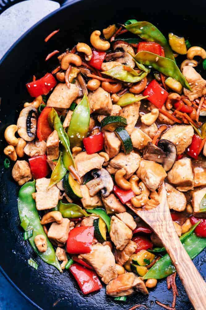 Cashew Chicken Stir Fry in a fry pan with a wooden spoon. 