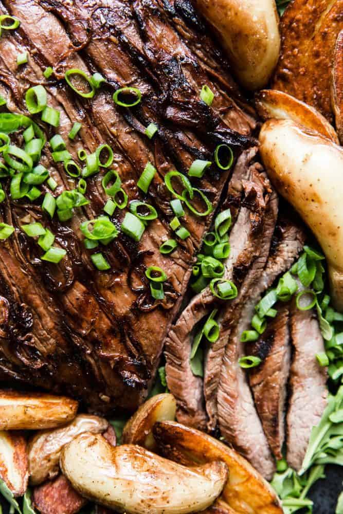 Close up of Brown Sugar Garlic Flank Steak with baked potato slices. 