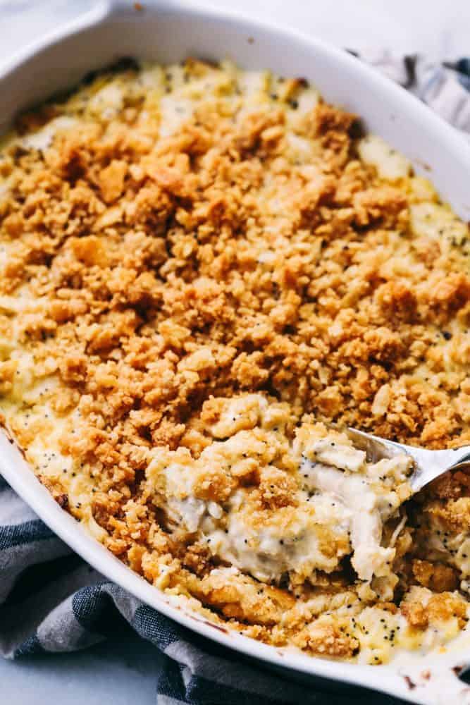 Poppyseed Chicken Casserole in a white platter with a metal spoon. 