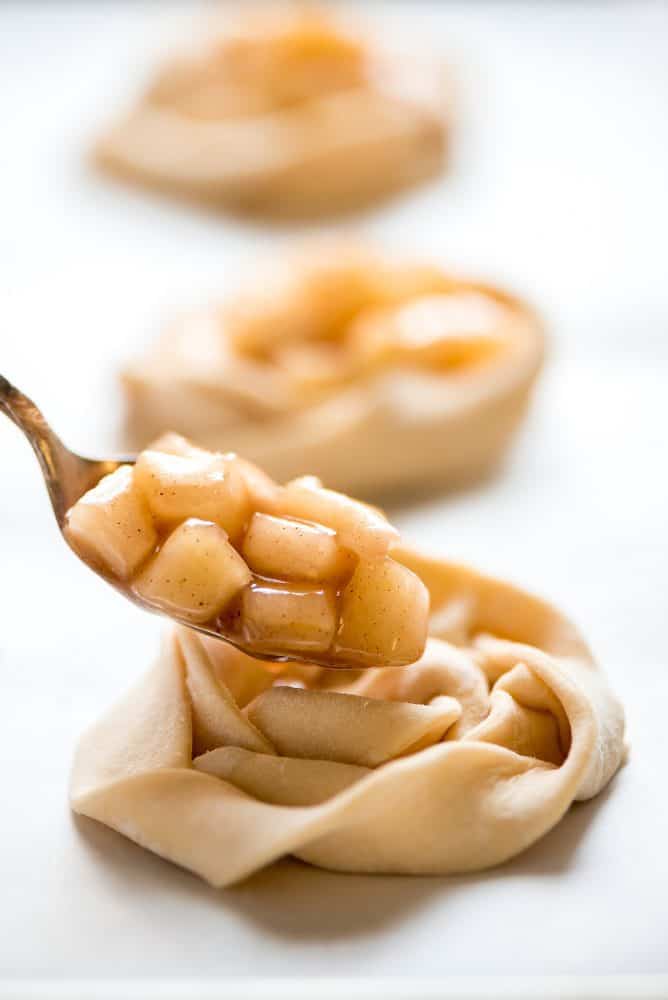 Close up of un-cooked apple filling being placed on the dough. 