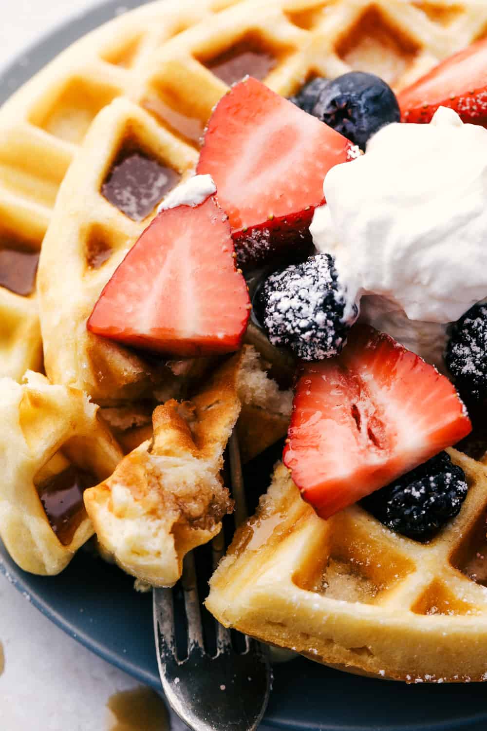 Upclose picture of syrup in the waffle holes and a bite being taken out.