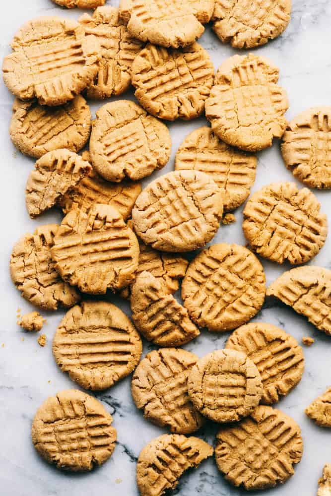 Several peanut butter cookies spread out on a white granite countertop.